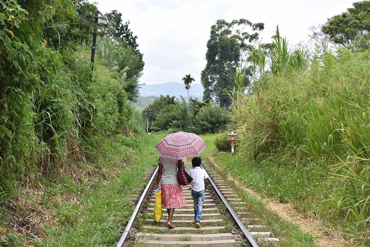 Eine sri-lankische Mutter mit Kind von hinten gesehen unterwegs zu Fuss.