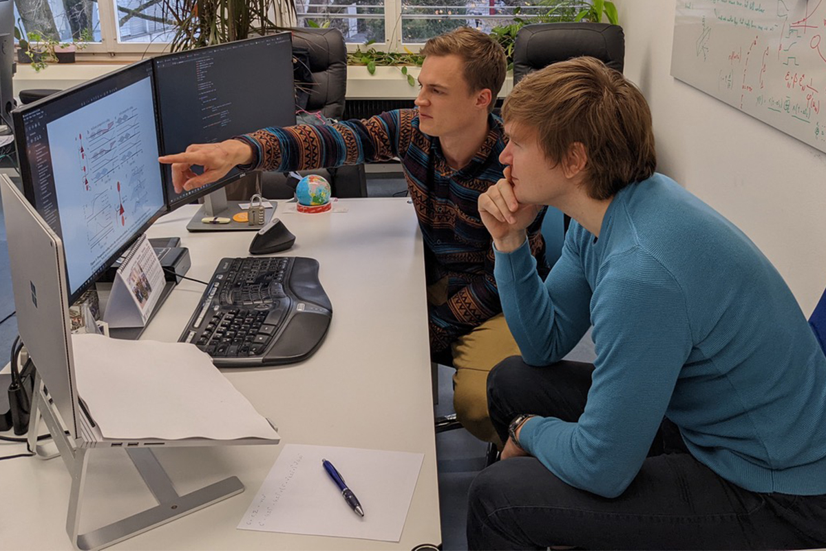 Mihai Petrovici (rechts) prüft mit dem Doktoranden Paul Haider eine Publikation über die Forschungsergebnisse ihrer neu entwickelten Algorithmen für künstliche neuronale Netzwerke. © zvg