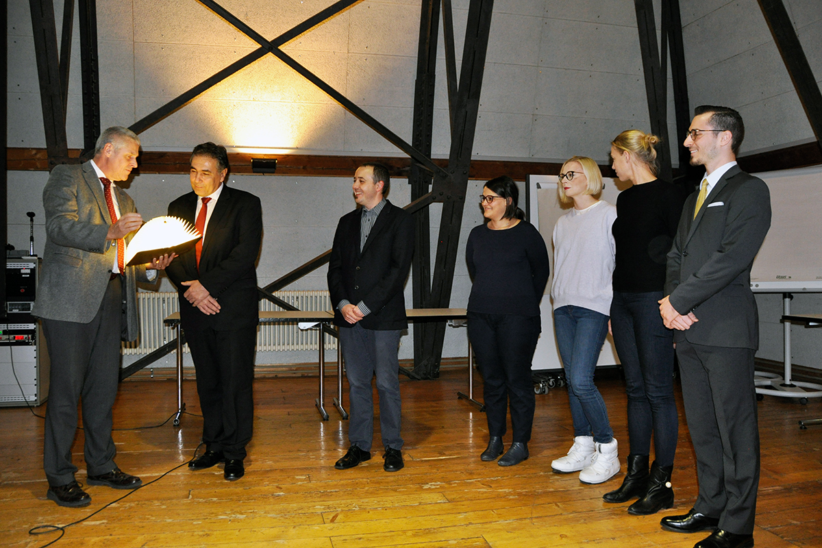 Der Preis in Form eines leuchtenden Buches wird Mihai Constantinescu und dem anwesenden Teil seines Teams vom Rektor überreicht.