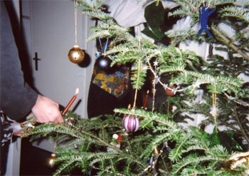 Person zündet Kerzen an Christbaum an