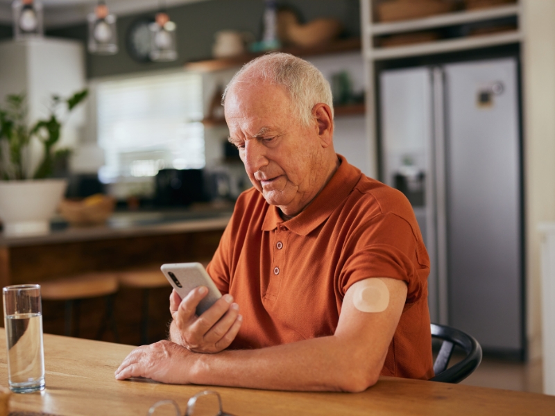 Mann mit Diabetes-Sensor redet in sein Smartphone